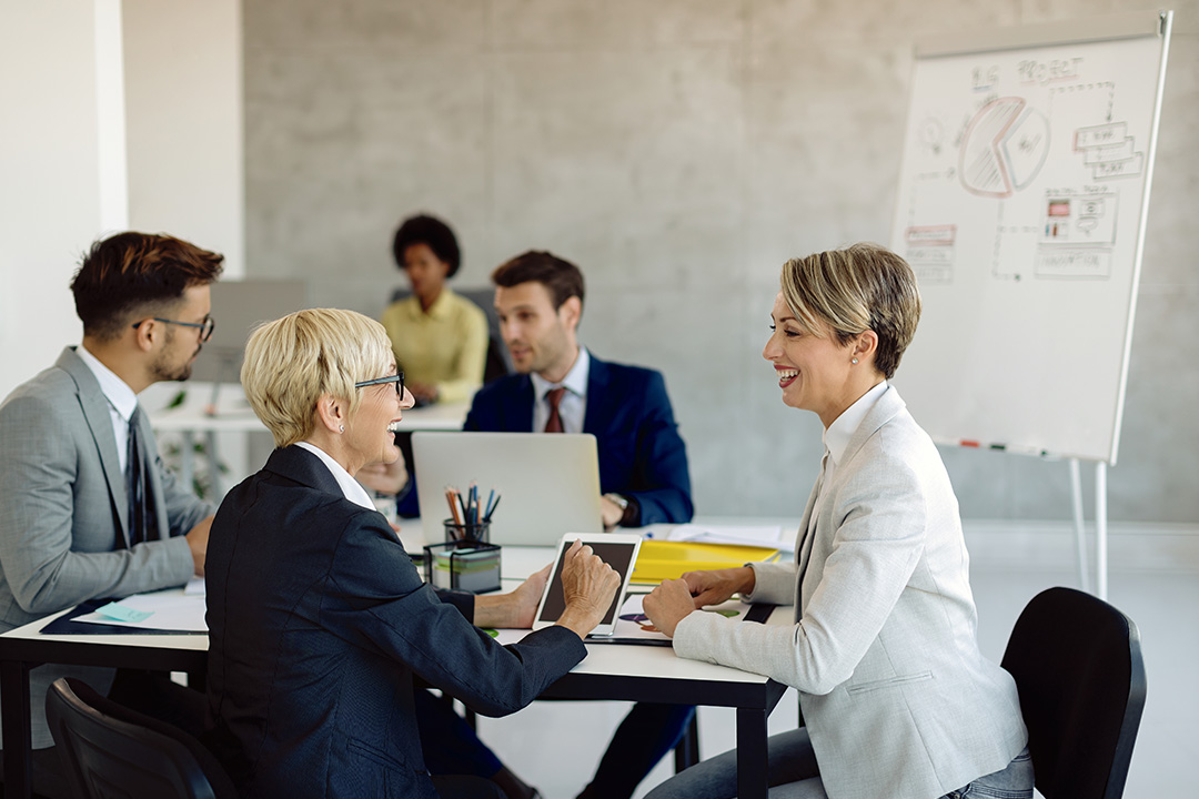 Two women smiling and having a conversation in a classroom environment