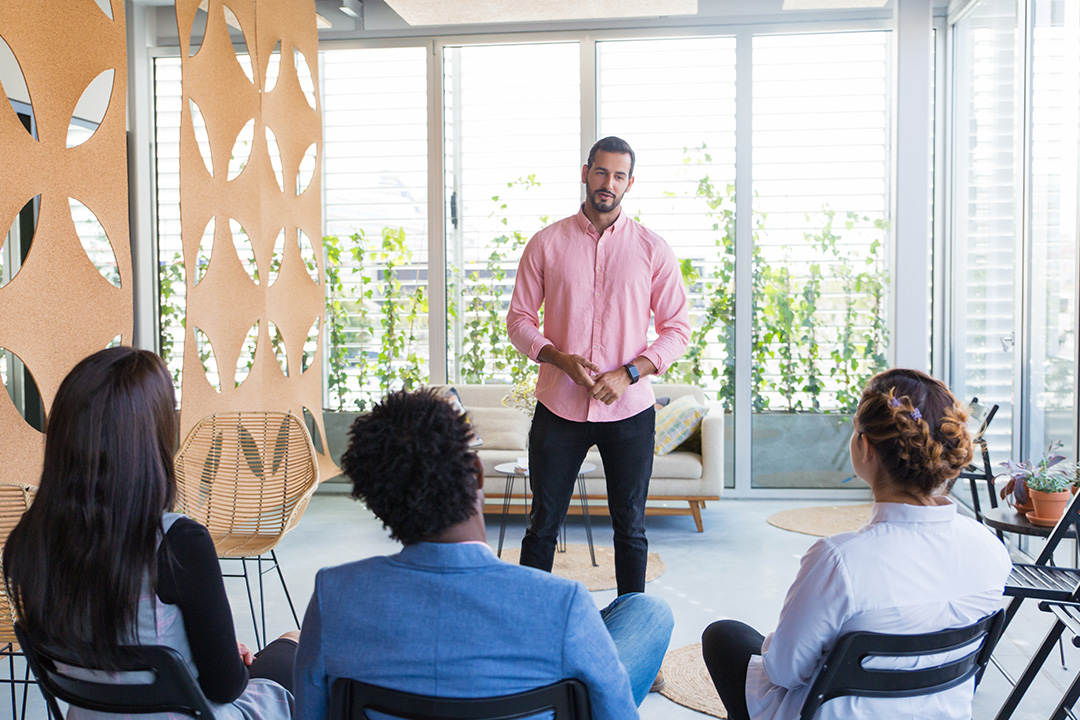 Man delivering course to three students in well lit room