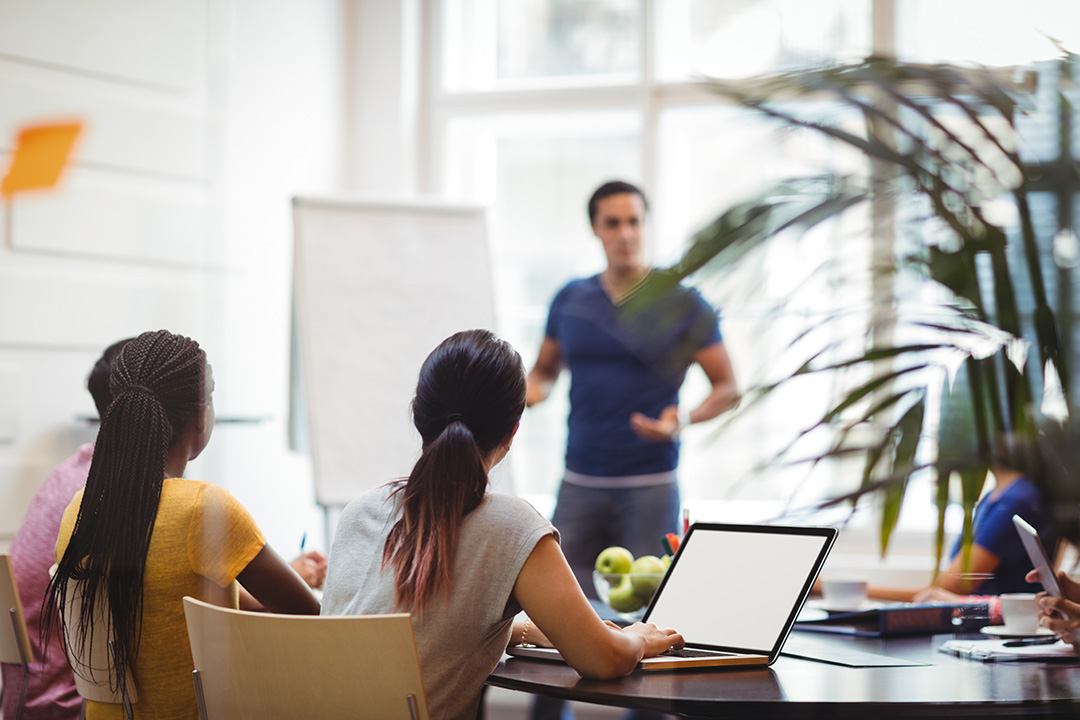 People attending a training course listening to the trainer at a desk
