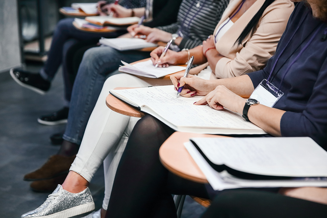 Close up of multiple people studying in classroom with papers and pens